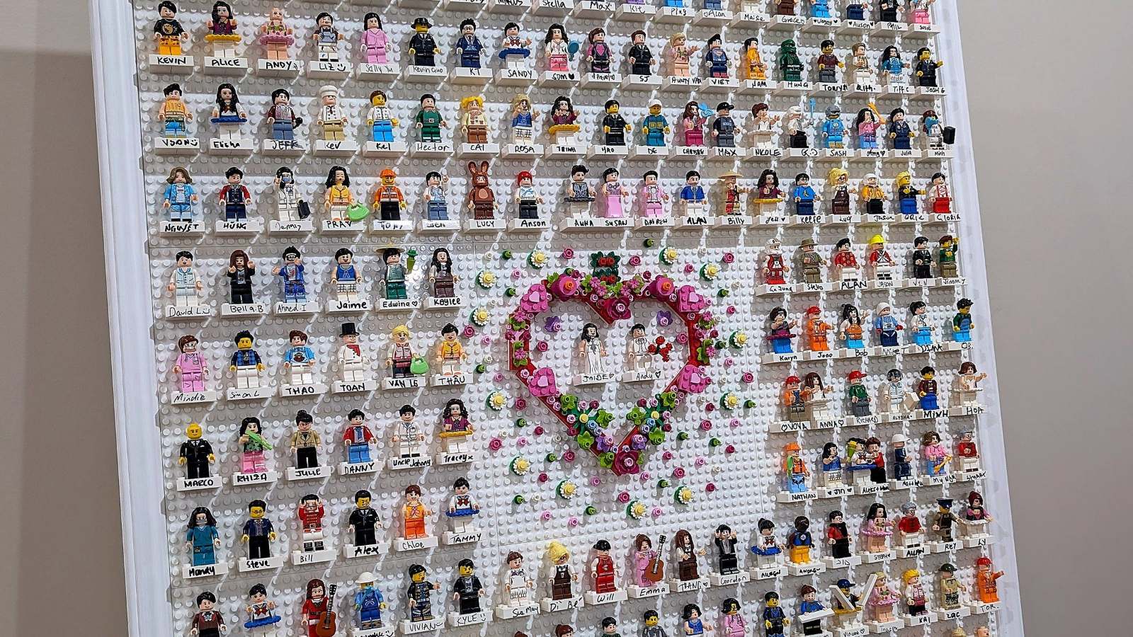 The finished brick guestbook — hundreds of named brick figures placed by wedding guests around a floral brick heart, with the couple at the centre.