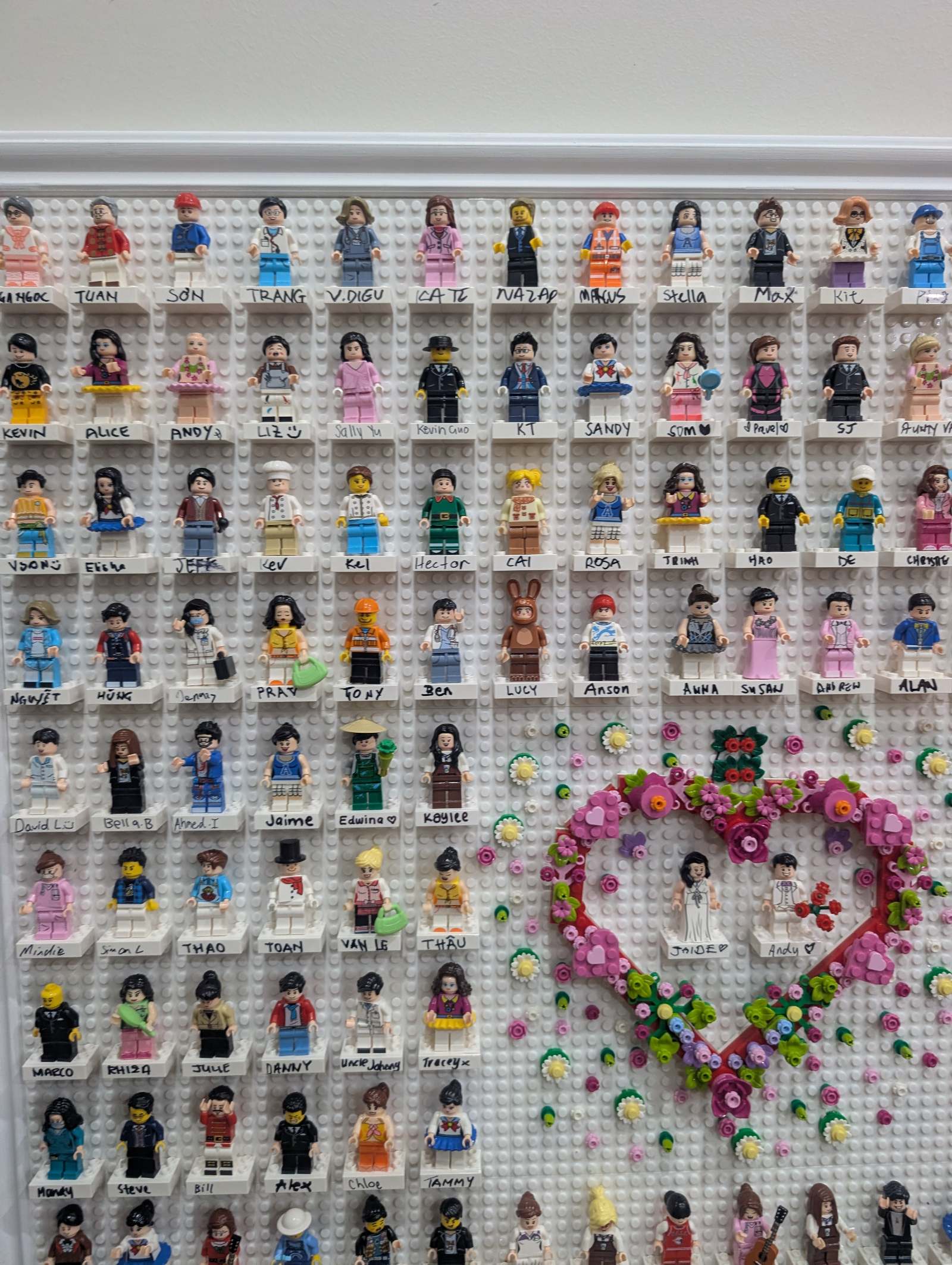 Close-up of the brick guestbook — rows of named guest brick figures around a flower-covered brick heart holding the couple's two custom figures.