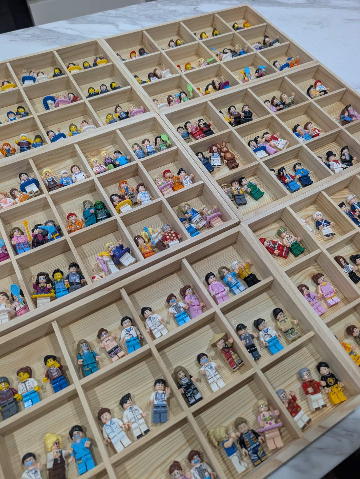Wooden trays of brick figures sorted by colour and style, ready for the night.